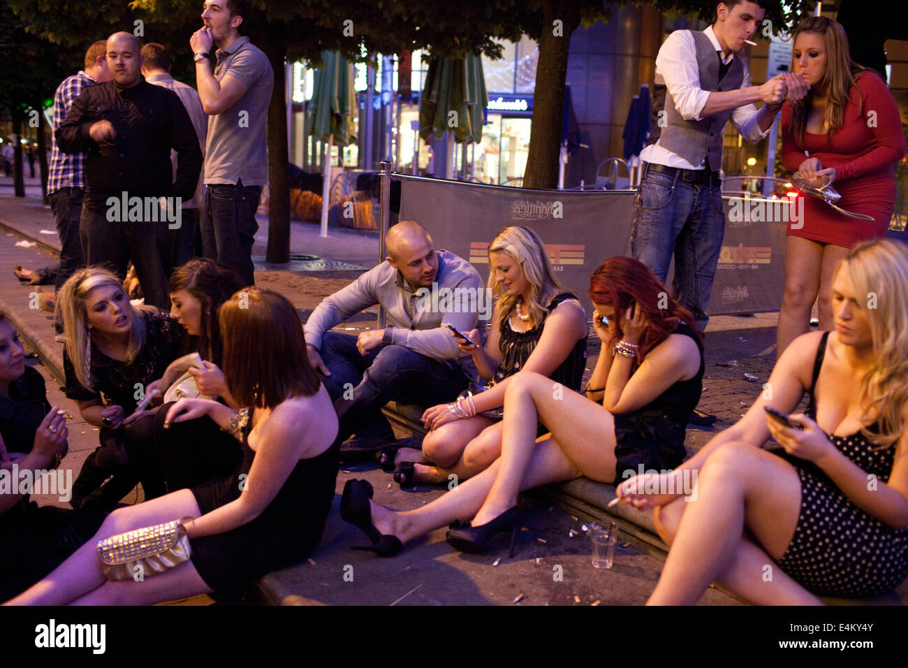 Un groupe de jeunes à discuter et fumer à l'extérieur d'un club de nuit un soir de fin de semaine dans la région de Cardiff, Pays de Galles, Royaume-Uni Banque D'Images