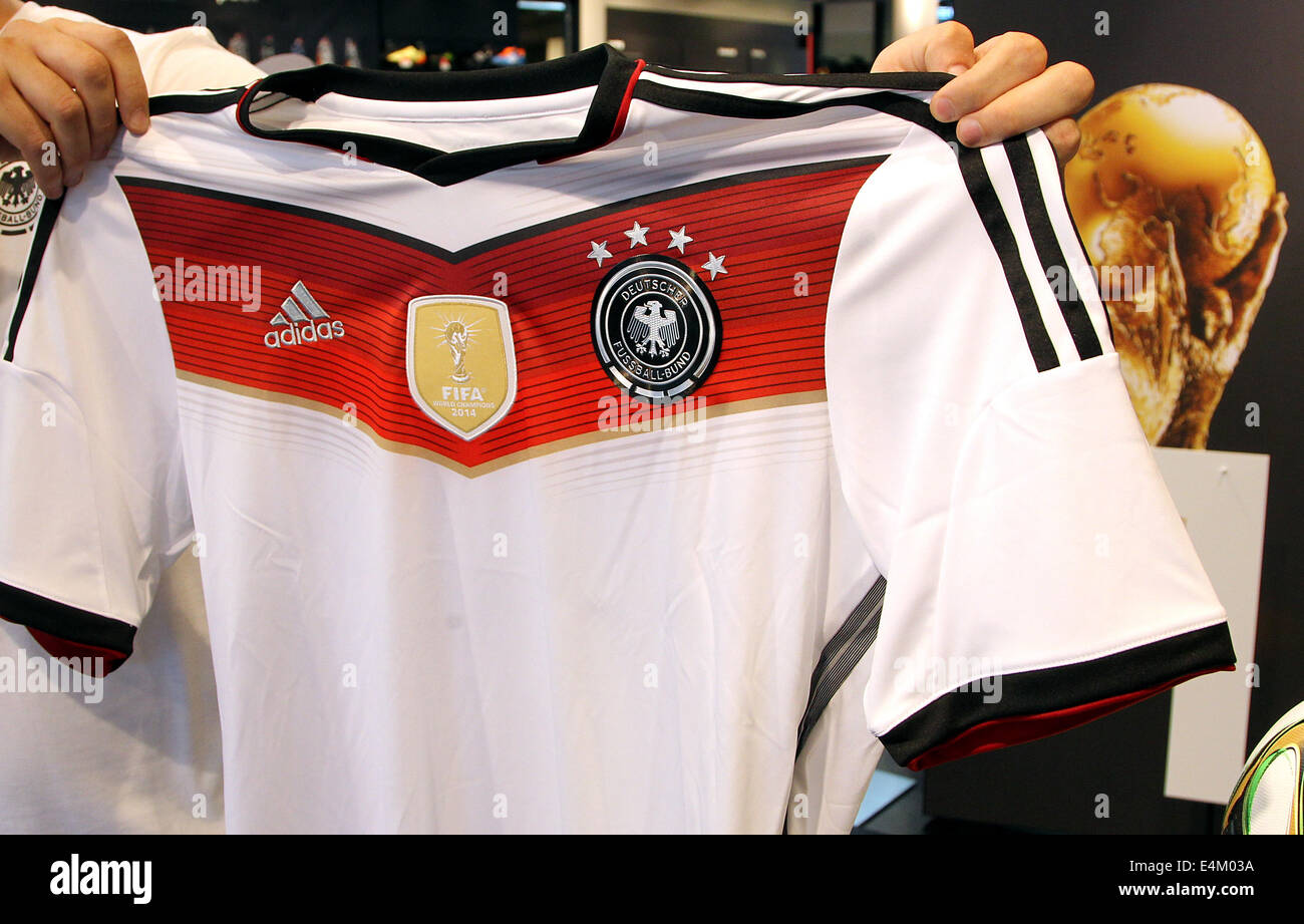 Berlin, Allemagne. 14 juillet, 2014. Un employé de la boutique adidas au  Tauentzien présente un maillot de l'équipe nationale de football allemande  avec la quatrième étoile de Berlin, Allemagne, 14 juillet 2014.