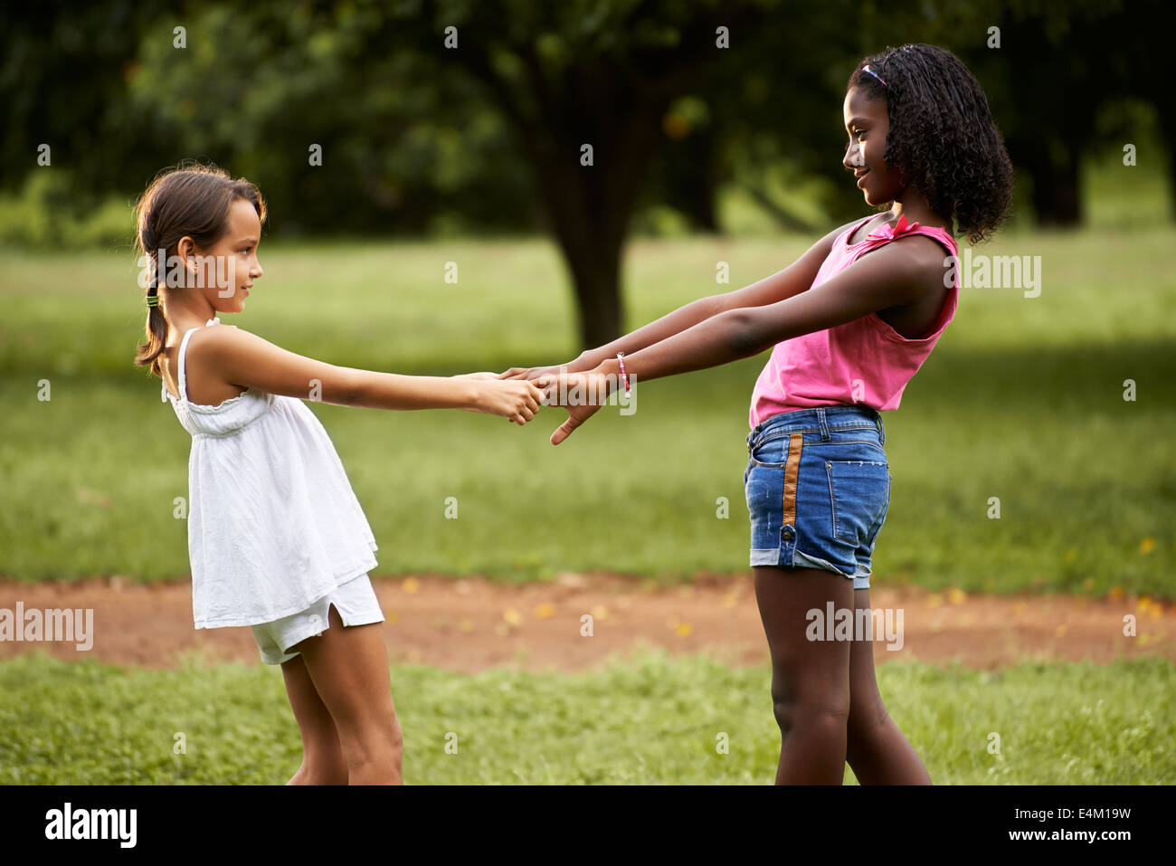 Deux petites filles hispaniques et africains jouant dans le parc public et tenir la main Banque D'Images