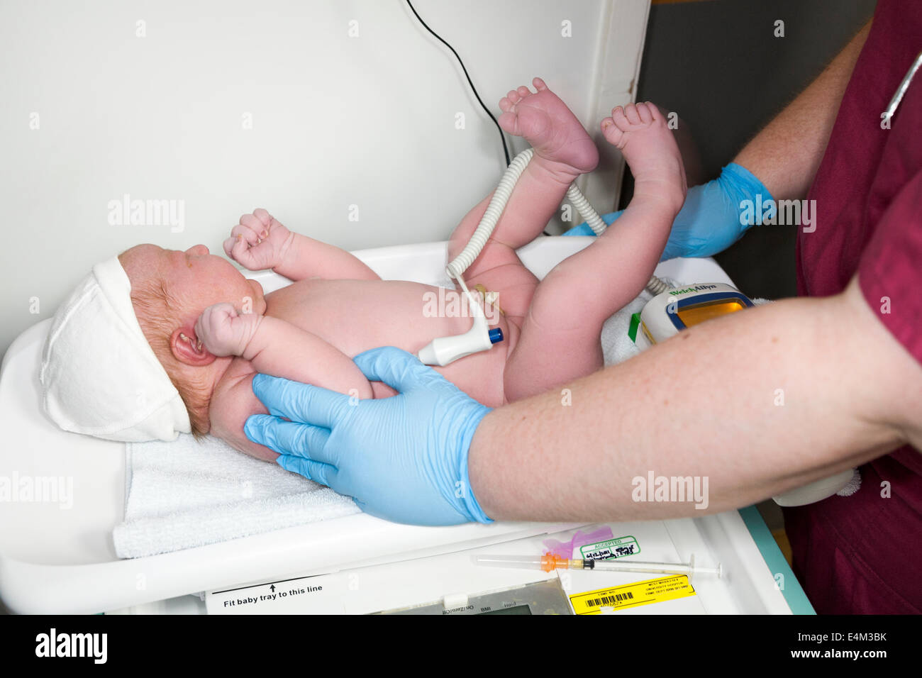 Les mains d' sage-femme effectuer un examen physique health check test test sur le nouveau-né / bébé nouveau-né après la naissance de l'être né / UK Banque D'Images