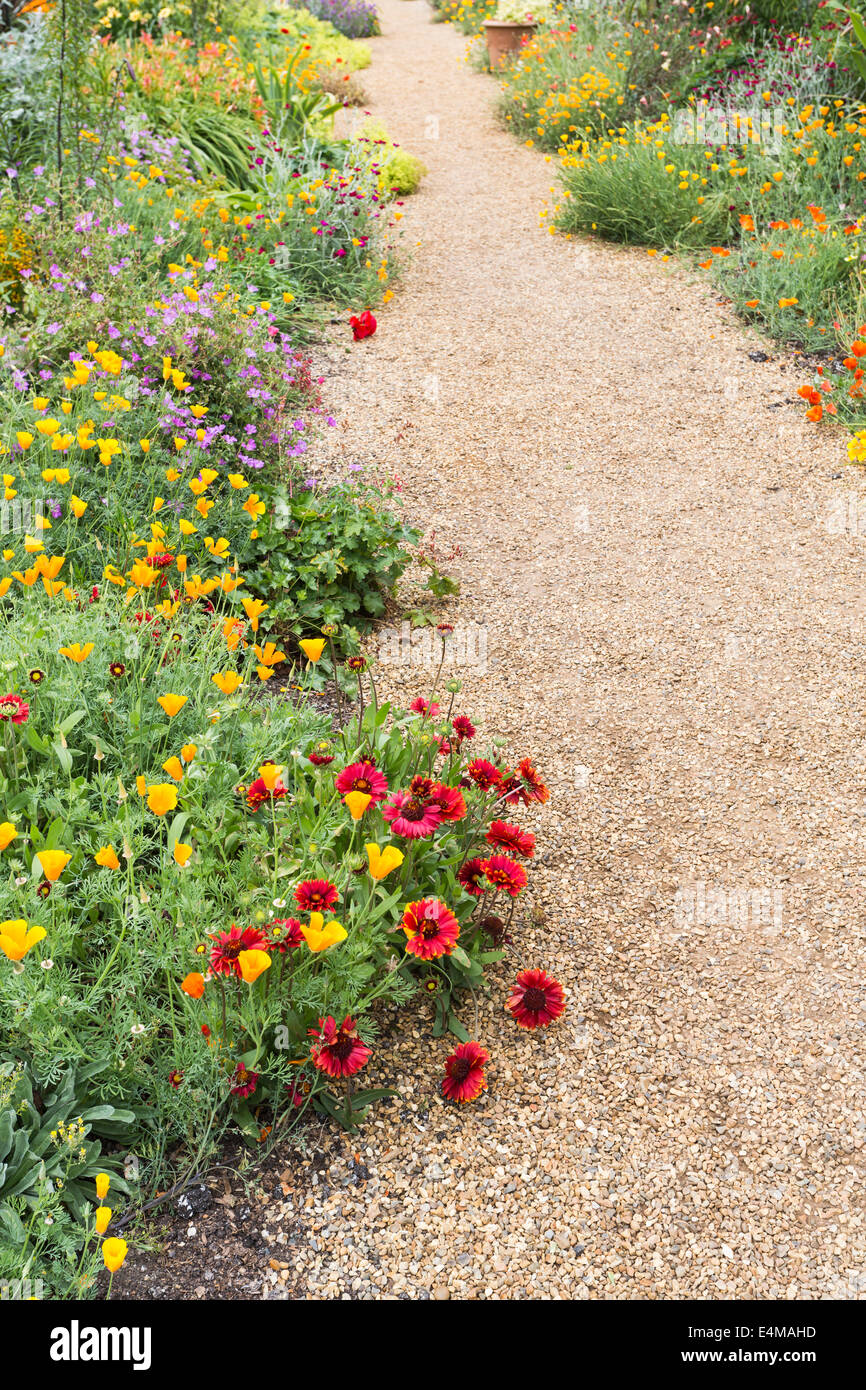 Fleurs d'été colorés débordent sur d'allée de graviers dans le jardin clos à Felbrigg Hall, Norfolk Banque D'Images