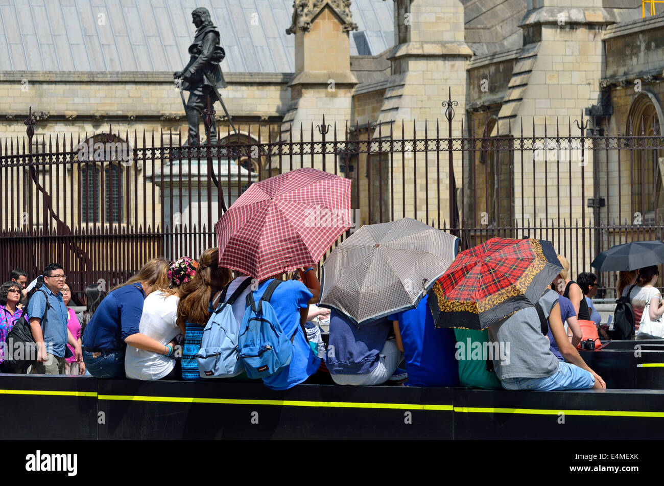 Londres, Angleterre, Royaume-Uni. Les touristes à l'abri du soleil par les Chambres du Parlement Banque D'Images