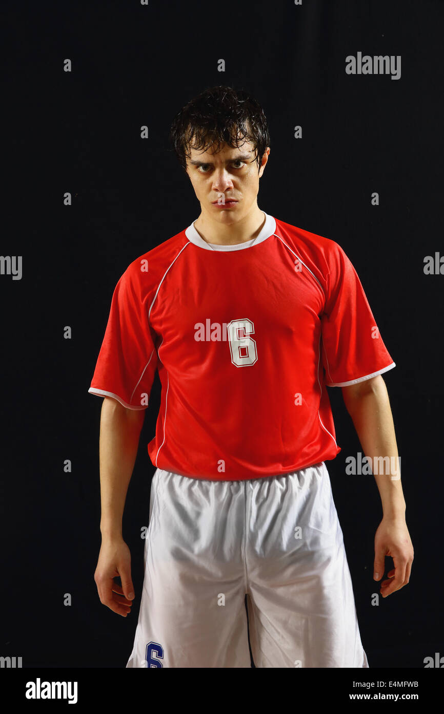 Joueur de football dans un uniforme blanc et rouge sur fond noir permanent Banque D'Images