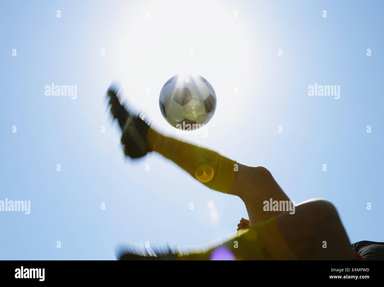 Football player kicking ball dans l'air Banque D'Images