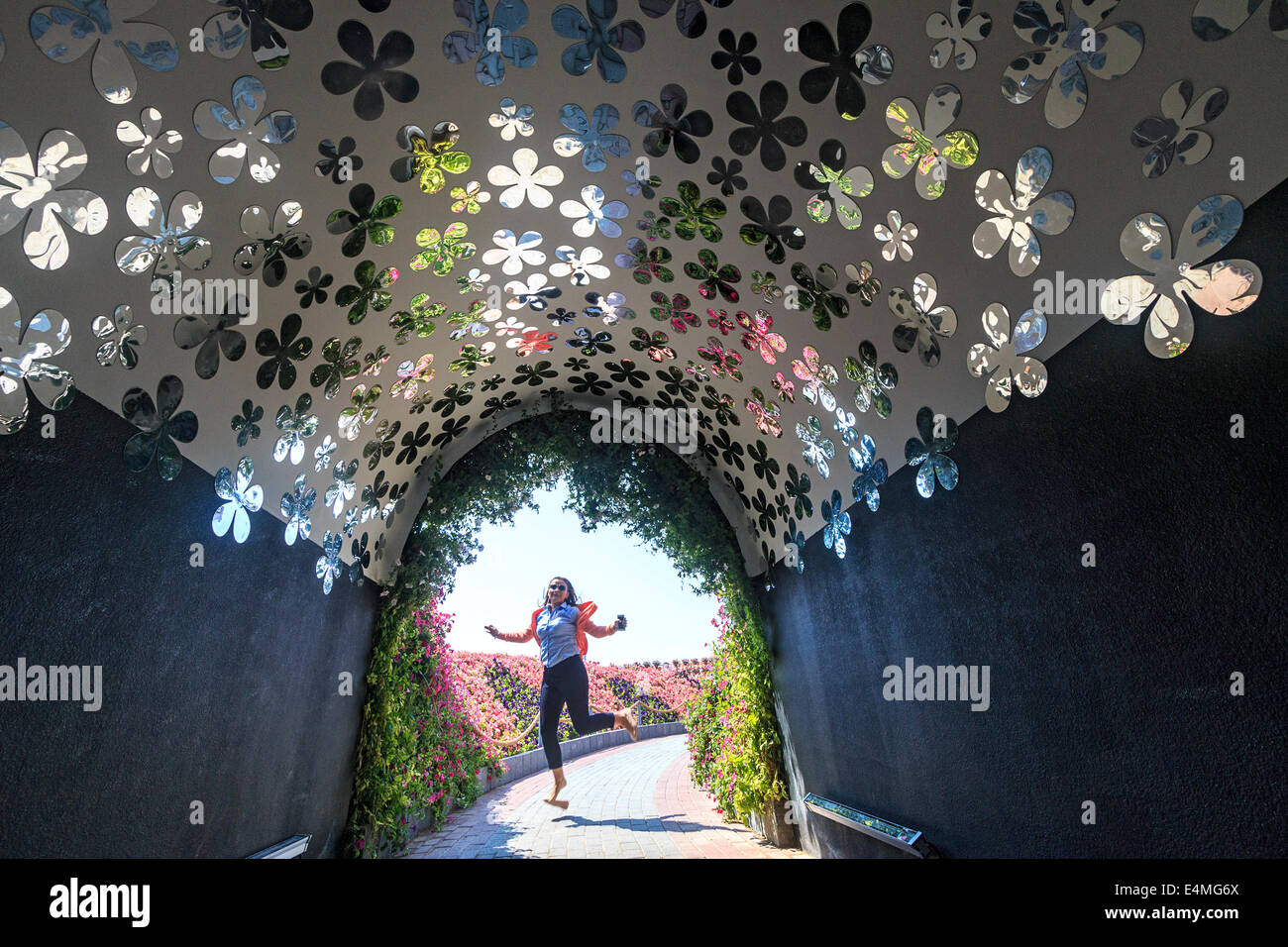 Tunnel de réflexion 'fleurs' reflètent les vraies fleurs à l'extérieur en tant que visiteur saute de joie à Dubai's Miracle jardin, Banque D'Images