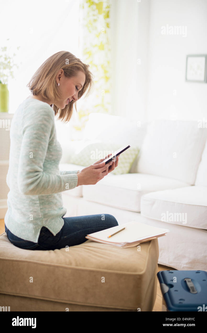 Femme assise dans la salle de séjour et using digital tablet Banque D'Images
