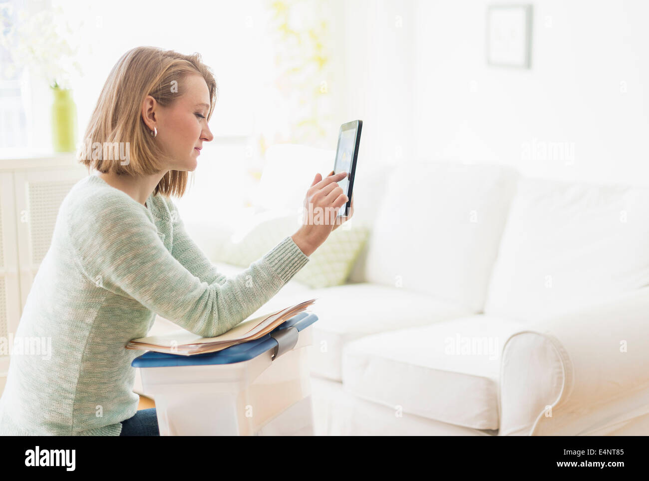 Femme assise dans la salle de séjour et using digital tablet Banque D'Images