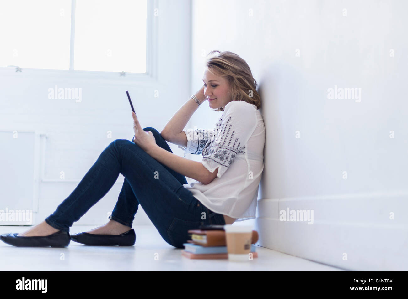 Young woman sitting on floor and using digital tablet Banque D'Images