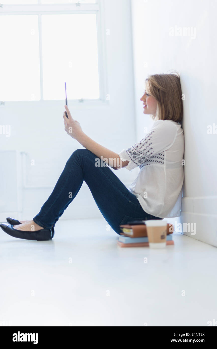 Young woman sitting on floor and using digital tablet Banque D'Images
