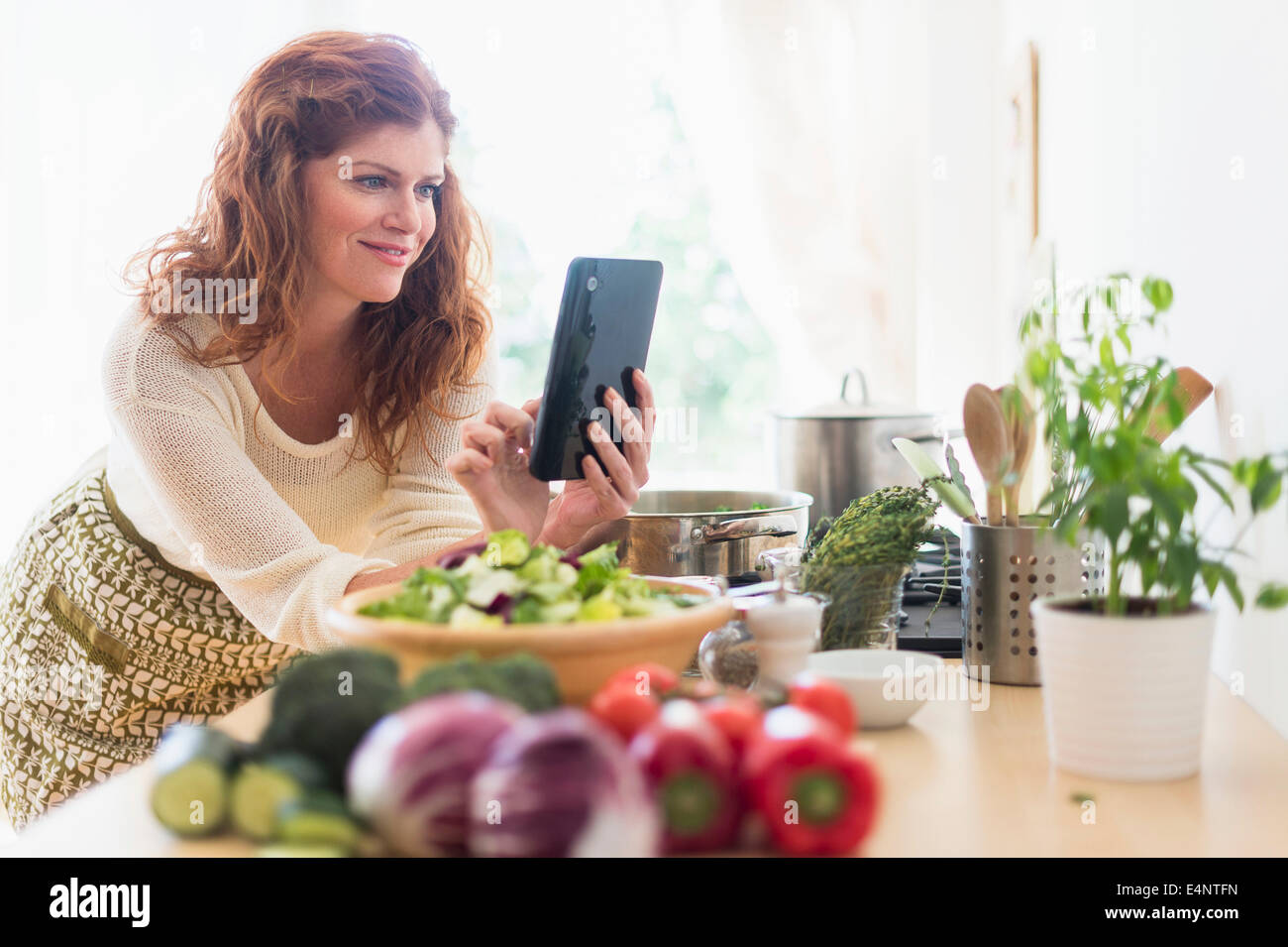 La cuisine femme et using digital tablet in kitchen Banque D'Images