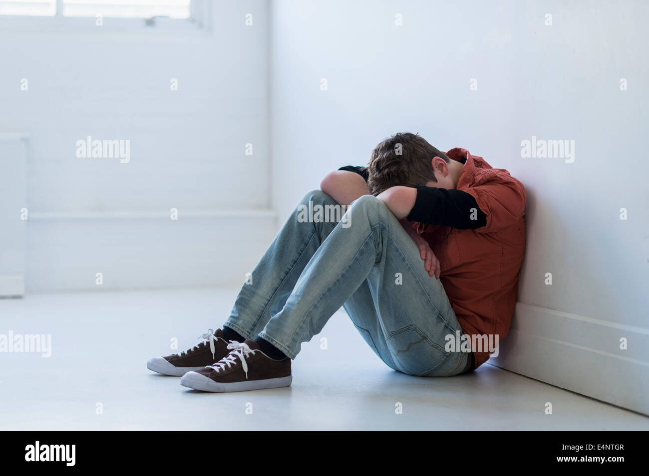 Teenage boy (16-17) assis dans le couloir Banque D'Images