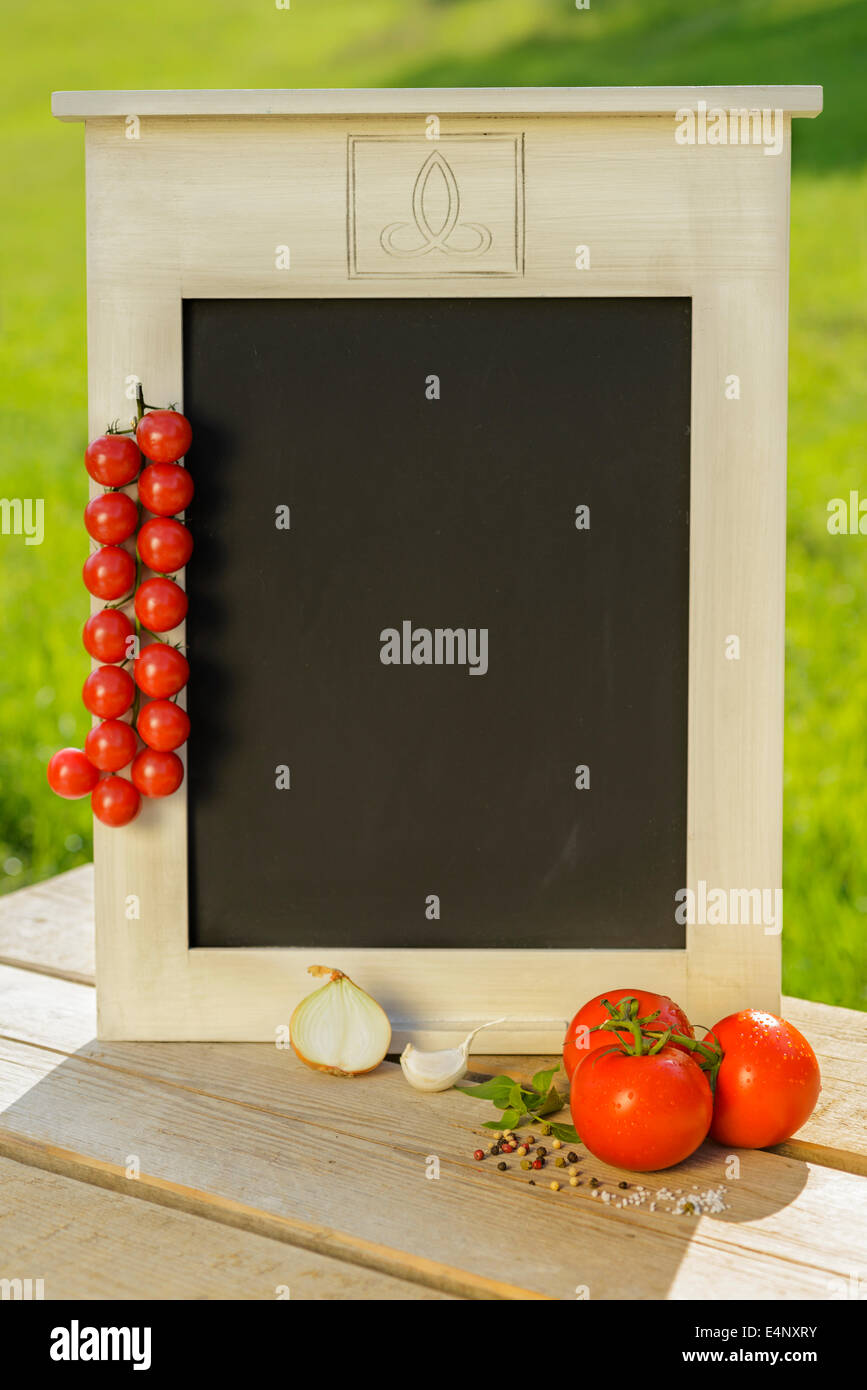 L'oignon tomate basilic ail épices herbes fraîches sel poivre tableau en bois tableau noir vert rouge sur la nutrition saine outdoor Banque D'Images