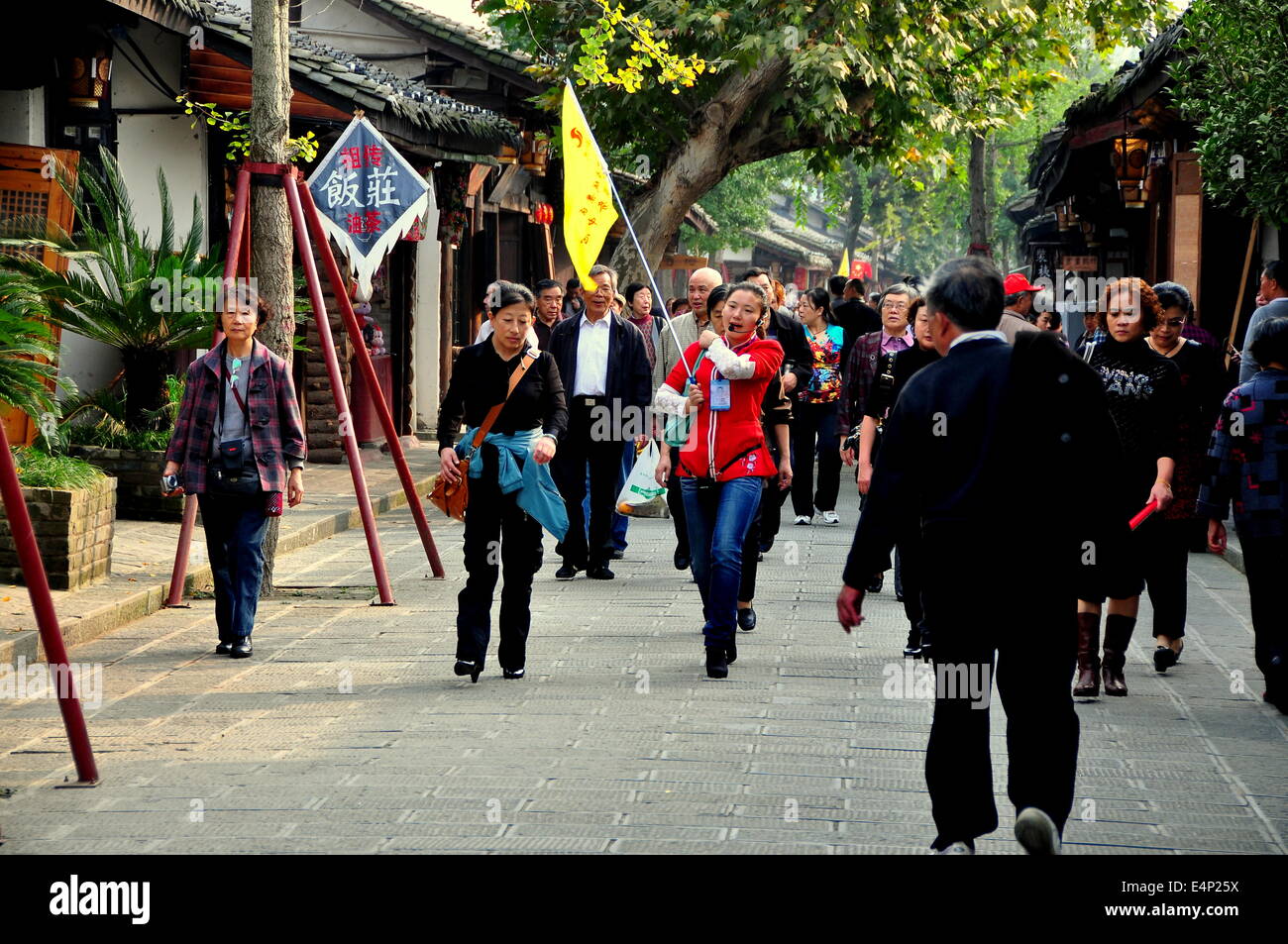 LANGZHONG VILLE ANCIENNE (Sichuan), Chine : guide touristique avec son drapeau jaune à la tête d'un grand groupe de touristes chinois Banque D'Images