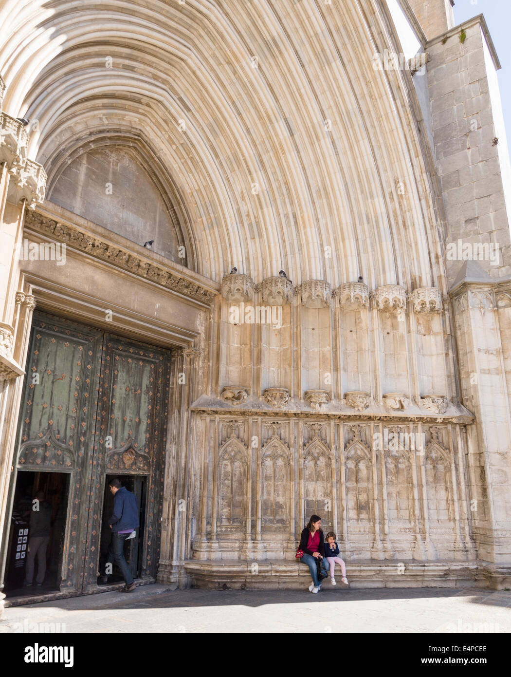 Entrée principale de la cathédrale de Gérone. Une mère et sa fille d'attendre à l'extérieur à l'ombre tout en un autre touriste entre dans Banque D'Images