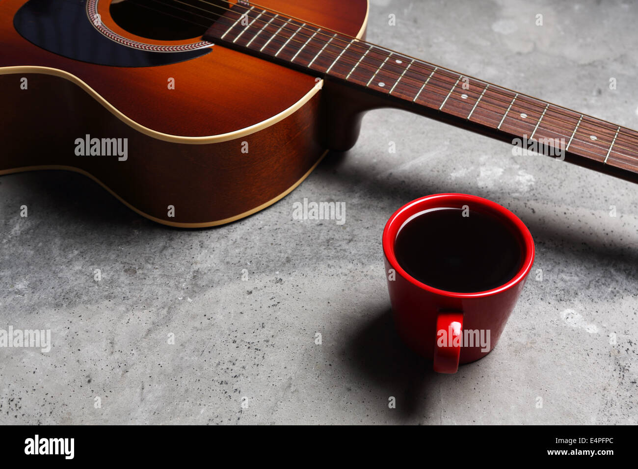 Une tasse de café chaud et une guitare sur une surface en béton. Banque D'Images