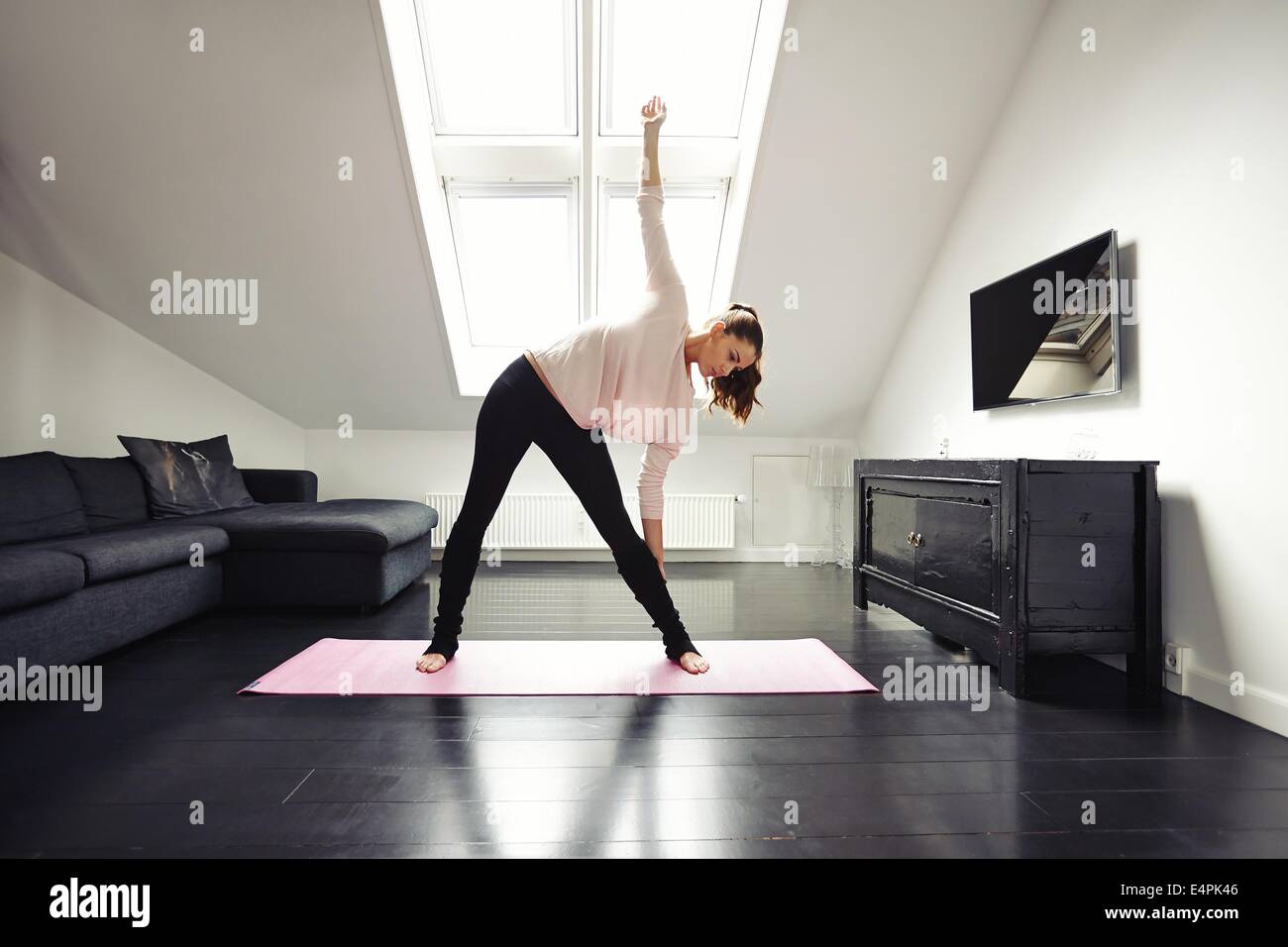 Fit young woman doing stretching exercer à son domicile. Modèle des femmes de race blanche en bonne santé l'exercice dans la salle de séjour. Banque D'Images
