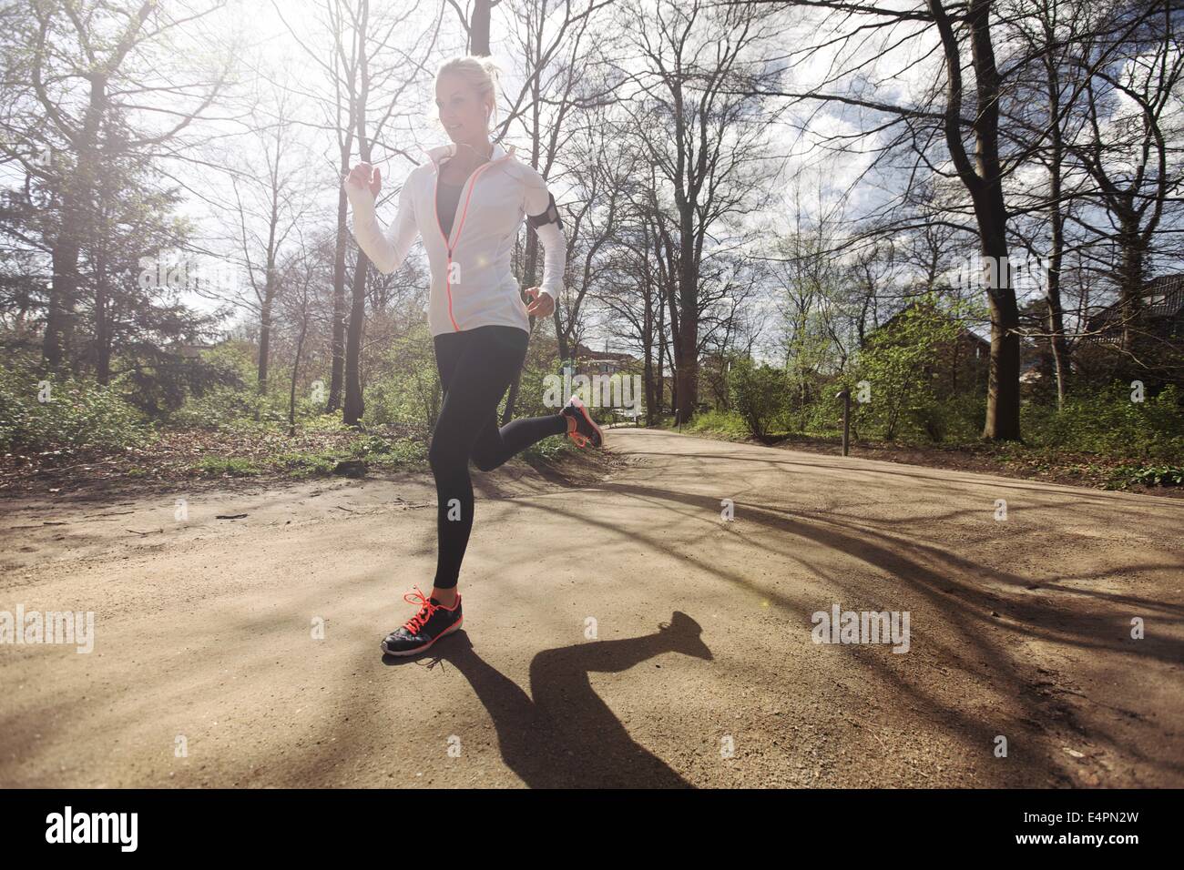 Young caucasian woman running à l'extérieur dans la forêt sur une journée ensoleillée. Mettre en place l'athlète féminine du jogging dans un parc. Caucasian female model tr Banque D'Images