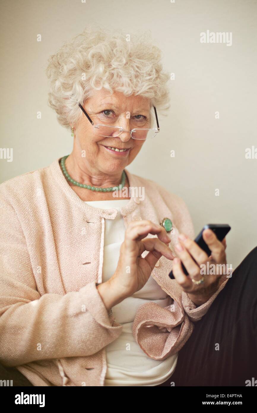 Vieille dame texting quelqu'un en utilisant son téléphone portable Banque D'Images