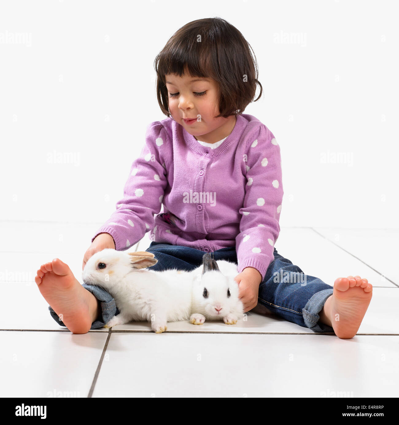 Fille (2 ans) avec deux bébés lapins blancs Banque D'Images