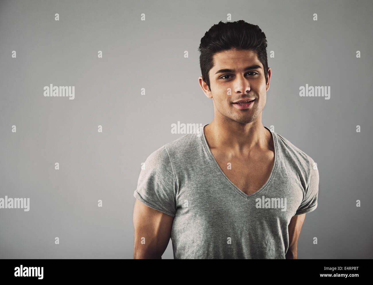 Portrait of handsome young hispanic male fashion model posing contre l'arrière-plan gris avec copie espace. Banque D'Images