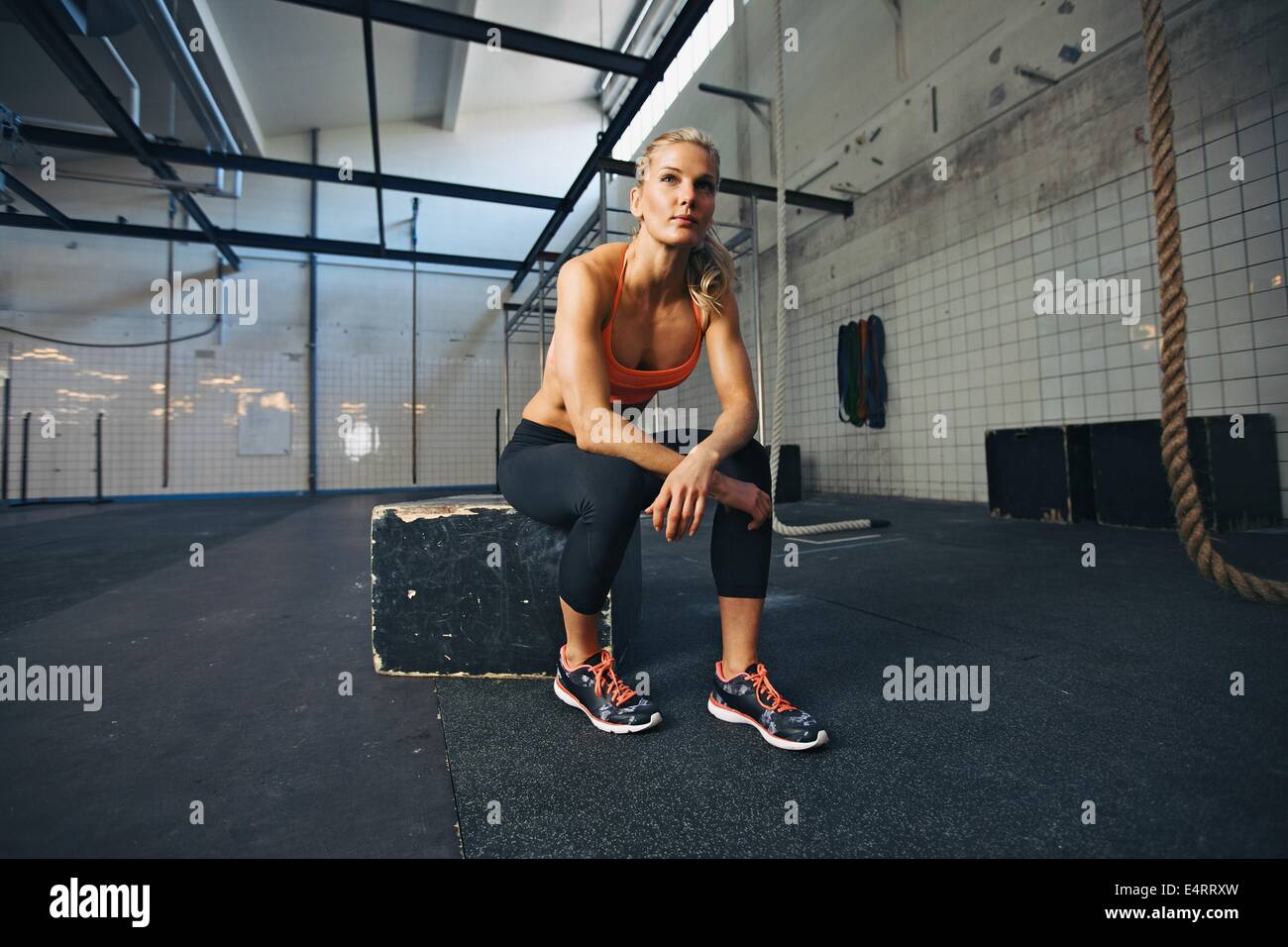 Jeune femme assise sur une boîte à crossfit gym à l'hôtel. Fit young caucasian female athlete au sport. Banque D'Images