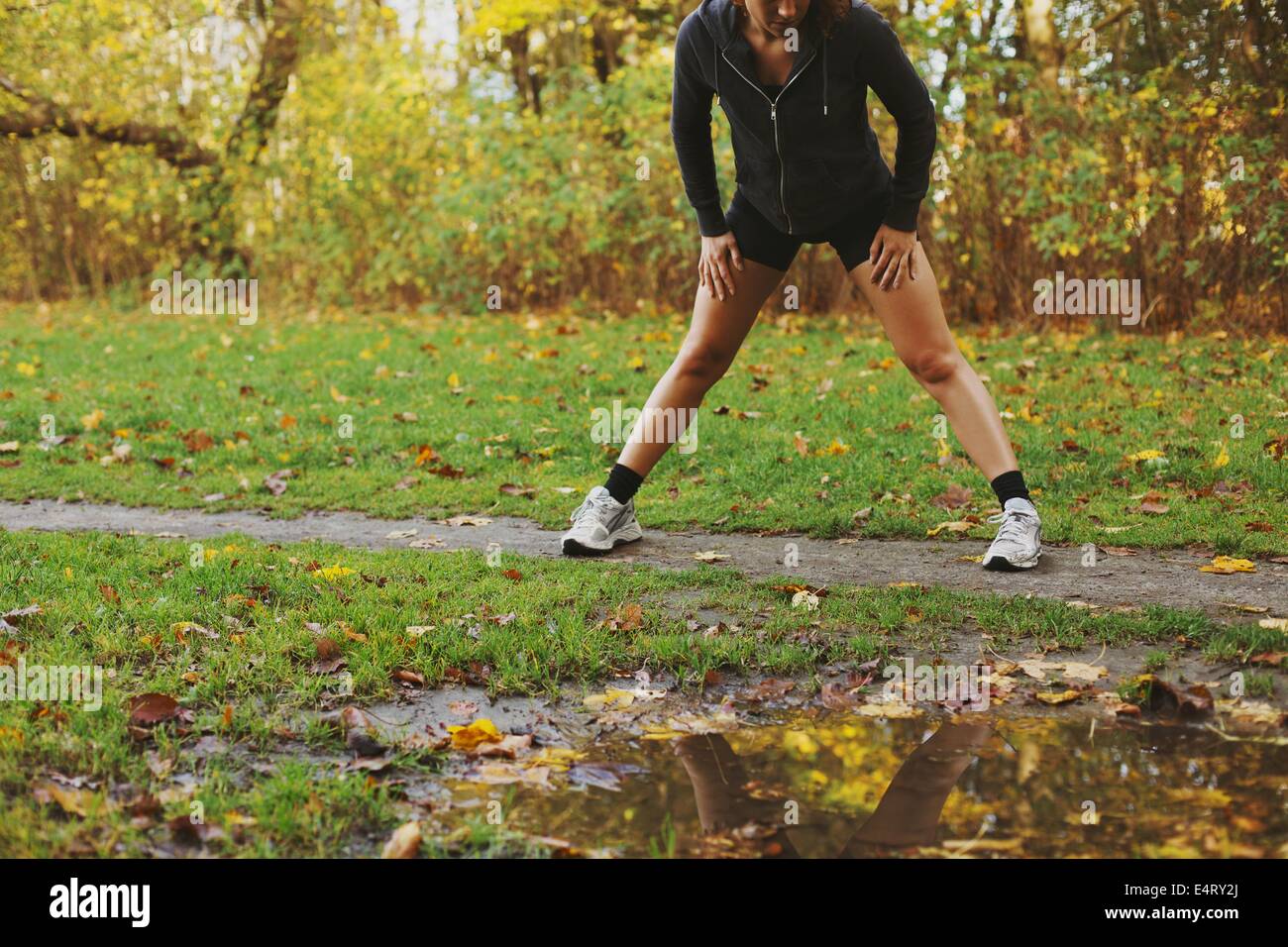 Jeune athlète féminine caucasienne s'étirant dans le parc en feuilles d'automne. femme de fitness faisant de l'exercice à l'extérieur Banque D'Images Jeune athlète féminine caucasienne s'étirant dans le parc en feuilles d'automne. femme de fitness faisant de l'exercice à l'extérieur Banque D'Images