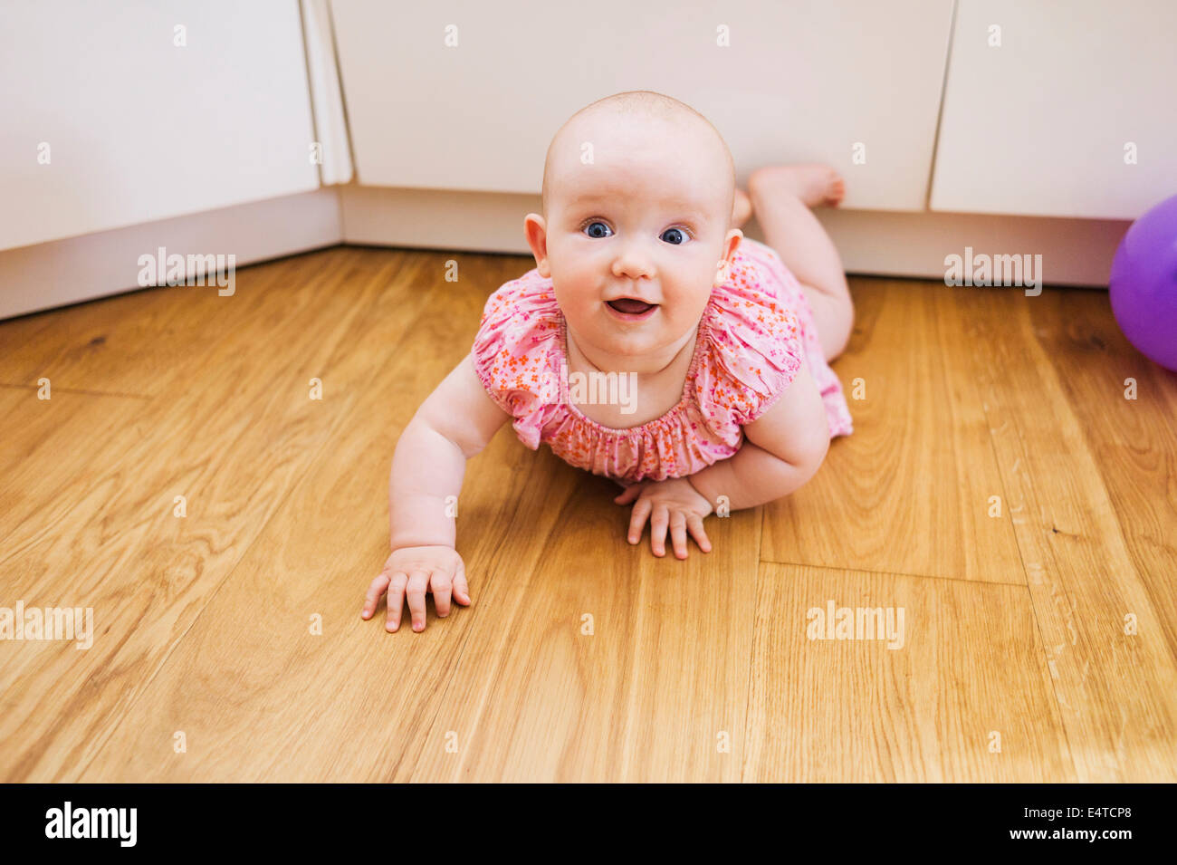 Portrait of Baby Girl lying on floor and Smiling at the Camera Banque D'Images