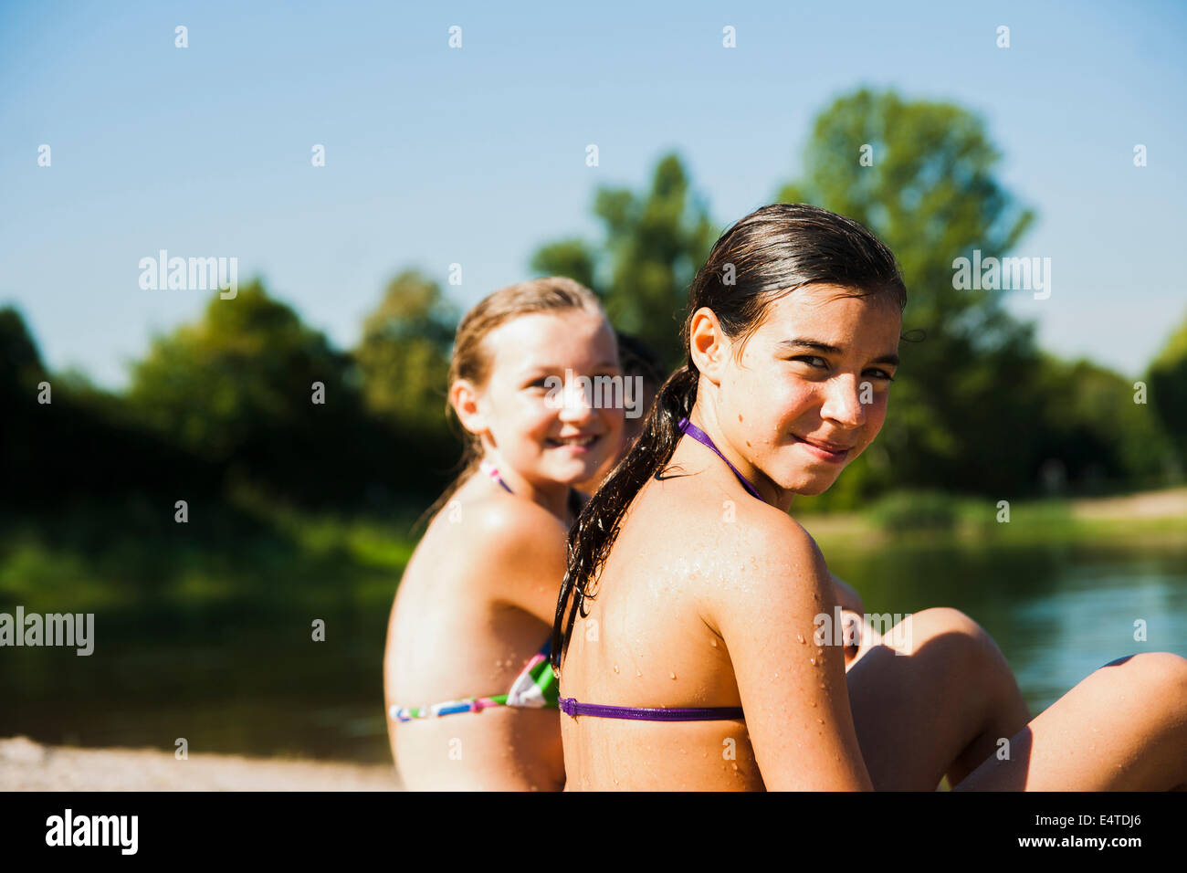 Close-up portrait of two girls sitting on beach at Lake, looking at camera and smiling, Lampertheim, Hesse, Allemagne Banque D'Images