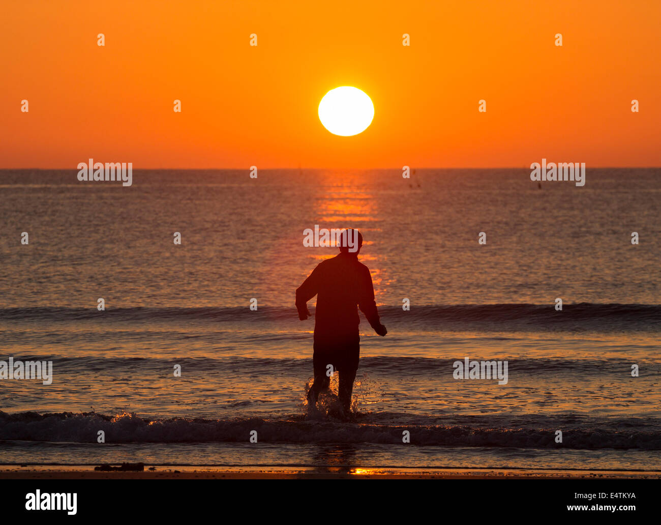 Seaton Carew près de Hartlepool, Angleterre, Royaume-Uni. 17 juillet, 2014. Météo britannique. Jogger de vous rafraîchir dans la mer à Seaton Carew comme le soleil se lève dans un ciel sans nuages sur une glorieuse jeudi matin sur la côte nord-est. Les températures sont appelées à progresser à 30 degrés Celsius dans le sud-est au cours des deux prochains jours d'orages violents le samedi. Credit : ALANDAWSONPHOTOGRAPHY/Alamy Live News Banque D'Images Seaton Carew près de Hartlepool, Angleterre, Royaume-Uni. 17 juillet, 2014. Météo britannique. Jogger de vous rafraîchir dans la mer à Seaton Carew comme le soleil se lève dans un ciel sans nuages sur une glorieuse jeudi matin sur la côte nord-est. Les températures sont appelées à progresser à 30 degrés Celsius dans le sud-est au cours des deux prochains jours d'orages violents le samedi. Credit : ALANDAWSONPHOTOGRAPHY/Alamy Live News Banque D'Images