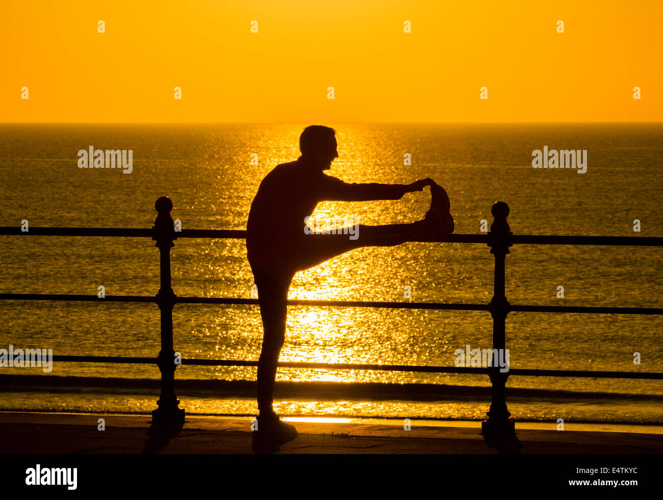 Seaton Carew près de Hartlepool, Angleterre, Royaume-Uni. 17 juillet, 2014. Météo britannique. Jogger stretching au lever du soleil sur un glorieux jeudi matin sur la côte nord-est. Les températures sont appelées à progresser à 30 degrés Celsius dans le sud-est au cours des deux prochains jours d'orages violents le samedi. Credit : ALANDAWSONPHOTOGRAPHY/Alamy Live News Banque D'Images Seaton Carew près de Hartlepool, Angleterre, Royaume-Uni. 17 juillet, 2014. Météo britannique. Jogger stretching au lever du soleil sur un glorieux jeudi matin sur la côte nord-est. Les températures sont appelées à progresser à 30 degrés Celsius dans le sud-est au cours des deux prochains jours d'orages violents le samedi. Credit : ALANDAWSONPHOTOGRAPHY/Alamy Live News Banque D'Images