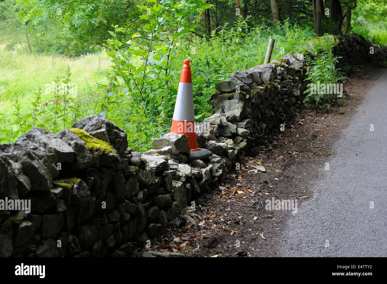 Dommages au mur en pierre en bordure de Derbyshire marqués d'un cône de circulation england uk Banque D'Images