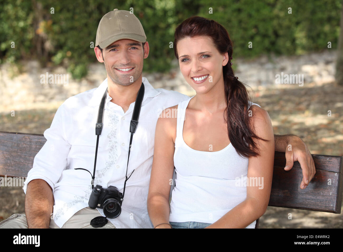 Couple assis sur un banc avec un appareil photo Banque D'Images