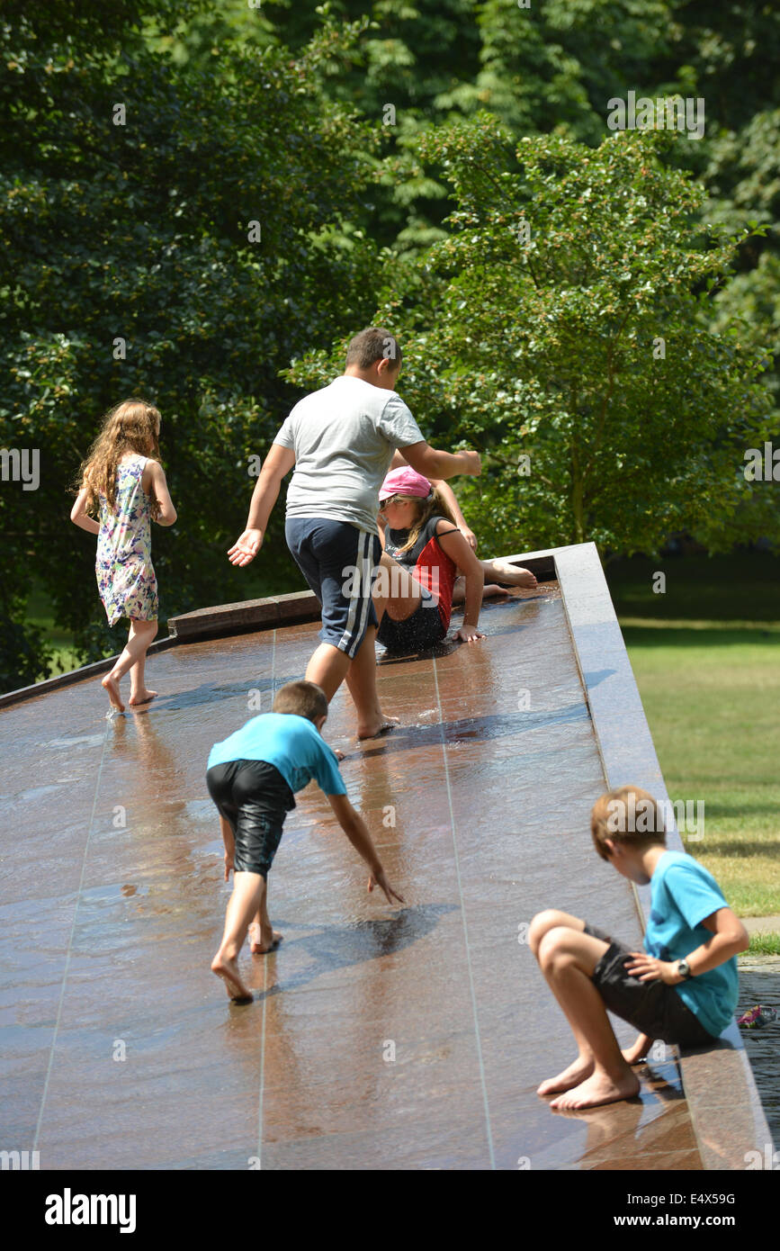 Green Park, London, UK. 17 juillet 2014. Les enfants jouissent de glisser vers le bas sur l'eau du monument commémoratif de guerre du Canada à Green Park. Crédit : Matthieu Chattle/Alamy Live News Banque D'Images