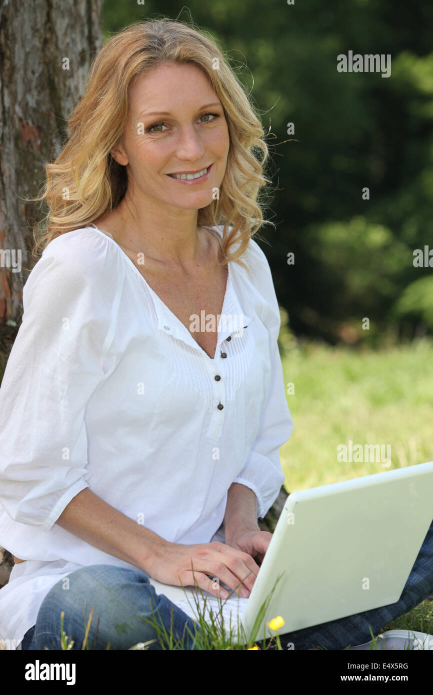 Woman on laptop under tree Banque D'Images