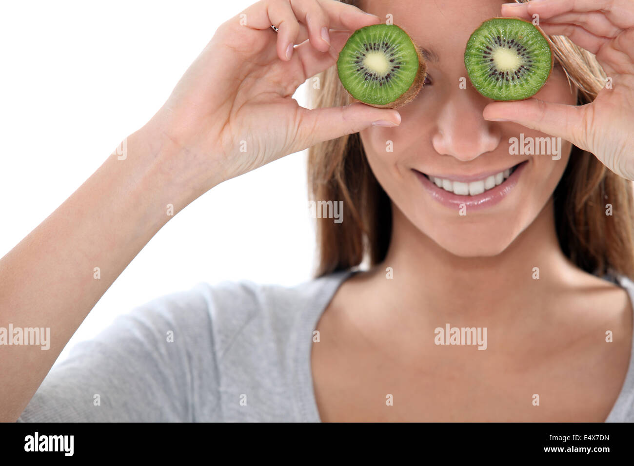 Femme couvrant ses yeux avec des tranches de kiwi Banque D'Images