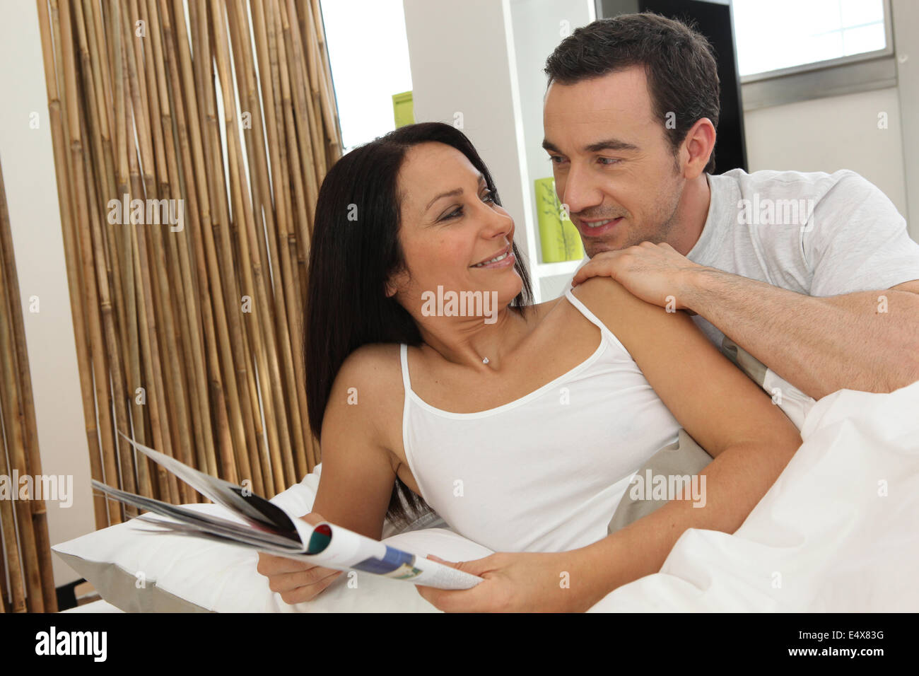 Couple in bed reading magazine Banque D'Images