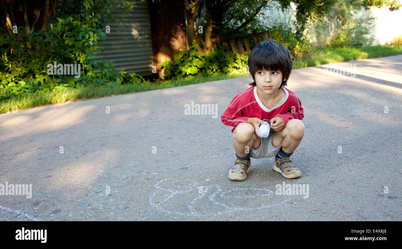 Boy drawing on asphalt Banque D'Images