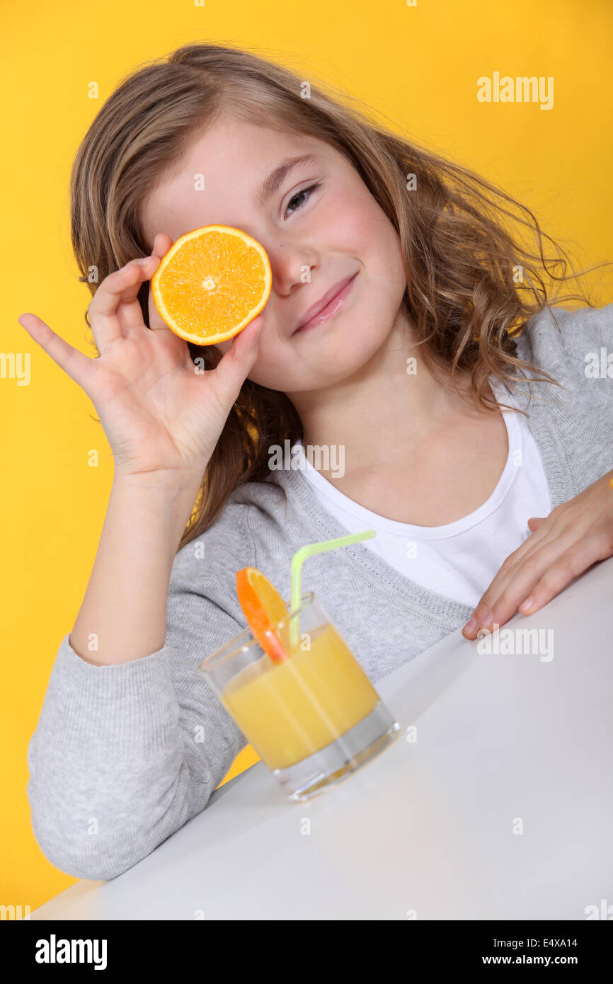 Couvrant son œil fille avec orange slice Banque D'Images