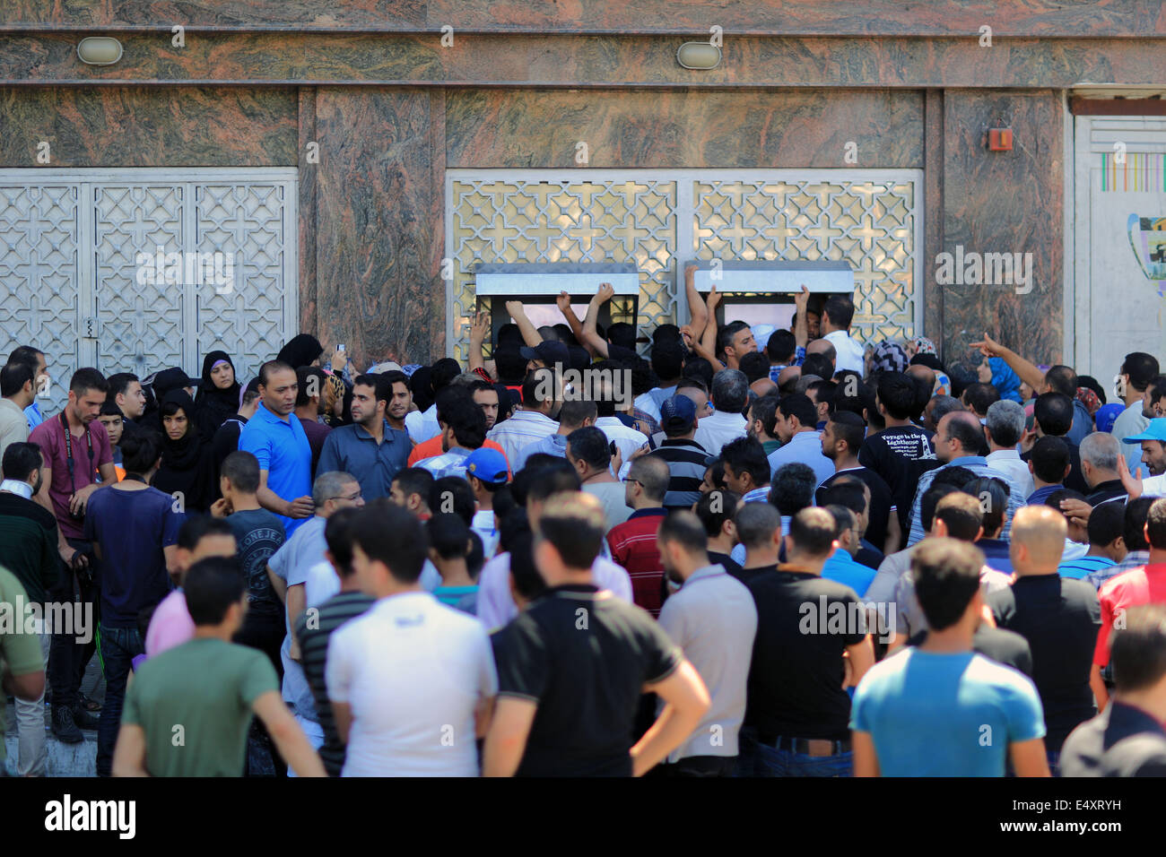 La bande de Gaza. 17 juillet, 2014. Essaim de Palestiniens de retirer leurs salaires à un distributeur automatique d'une banque pendant la durée de l'entente de cinq heures de cessez-le-feu humanitaire observée par Israël et le Hamas le 17 juillet 2014 dans la ville de Gaza. Au moins trois roquettes ont été lancées au sud d'Israël le conseil régional Eshkol le jeudi à midi, deux heures après les cinq heures de cessez-le-feu temporaire, les Forces de défense israéliennes (FDI). Source : Xinhua/Alamy Live News Banque D'Images