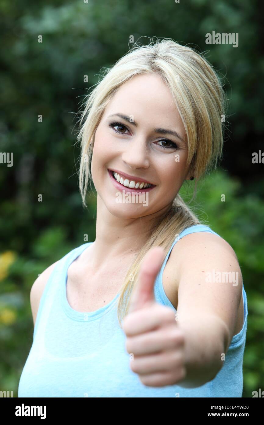 Belle femme souriante donnant un coup de pouce Banque D'Images