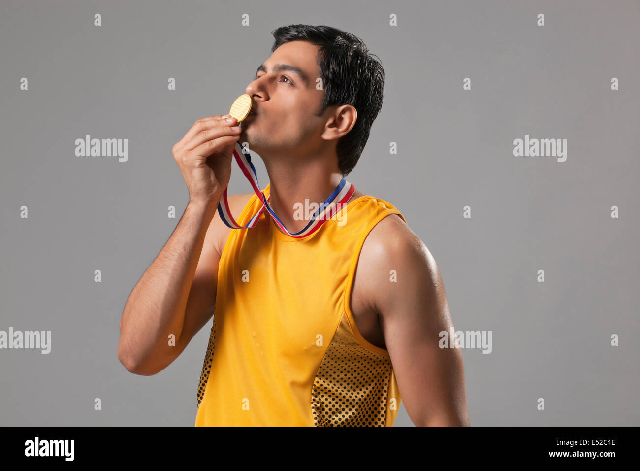 Jeune homme en embrassant l'usure taches isolées de la médaille d'or sur fond gris Banque D'Images