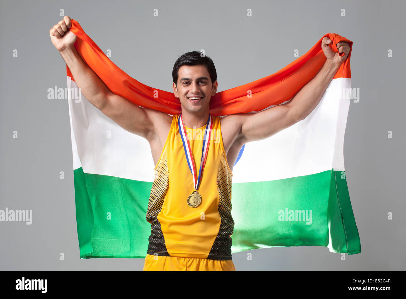 Portrait de l'homme célèbrent la victoire avec médaillé drapeau indien contre l'arrière-plan gris Banque D'Images