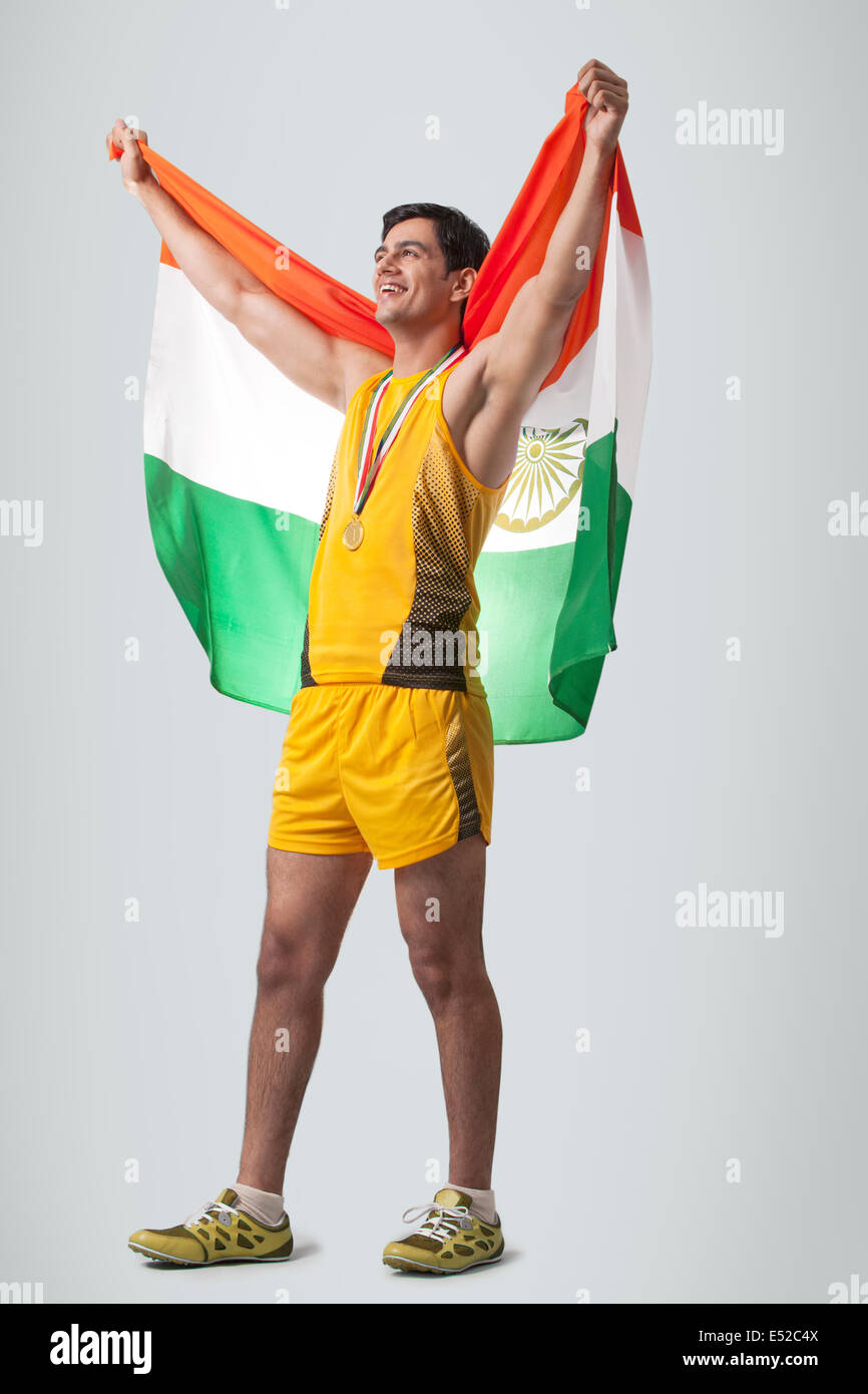 Heureux jeune homme célèbre médaillé la victoire avec drapeau indien isolé sur fond gris Banque D'Images