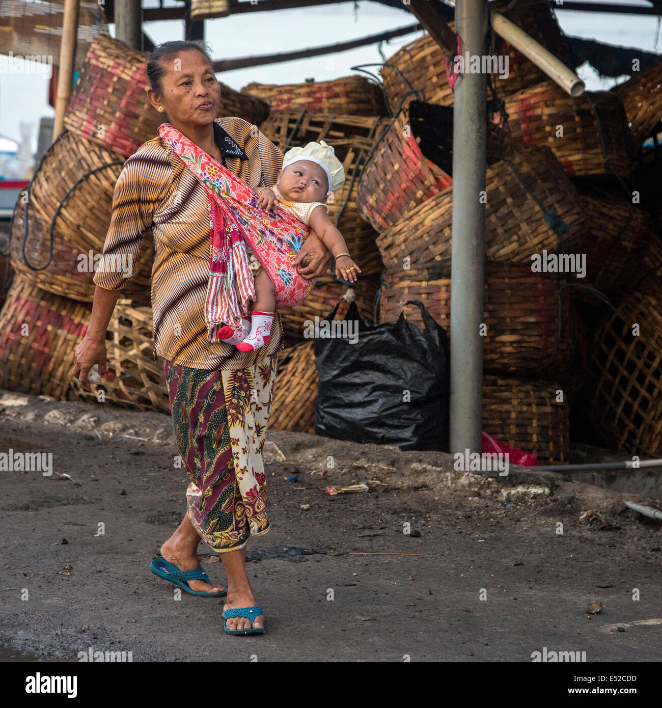 Bali, Indonésie. Femme transportant bébé dans un harnais d'épaule. Jimbaran. Banque D'Images