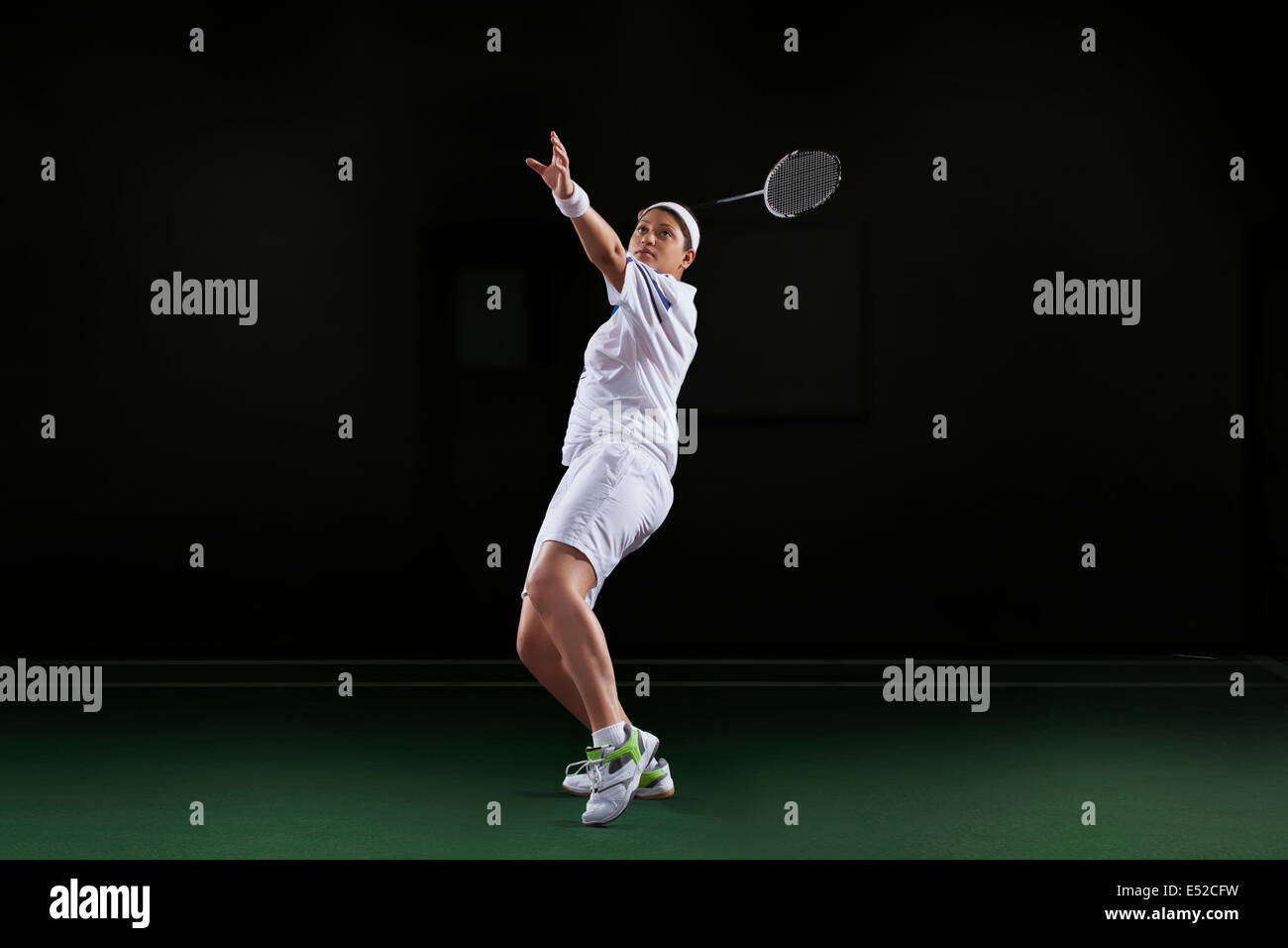 Vue latérale du jeune femme dans les vêtements de sport jouer au badminton sur fond noir isolé Banque D'Images