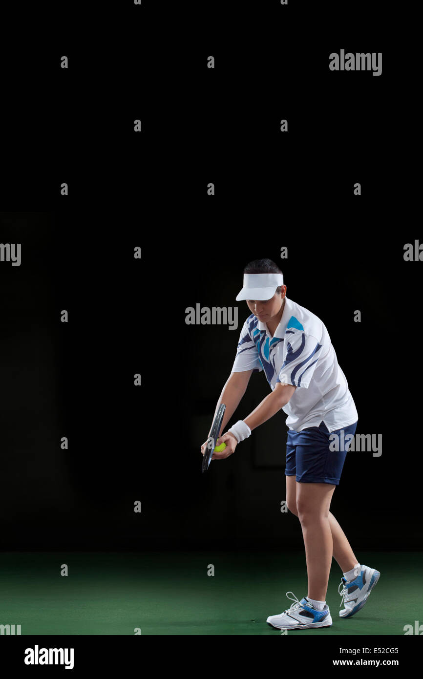 Tennis player prépare à servir sur fond noir Banque D'Images