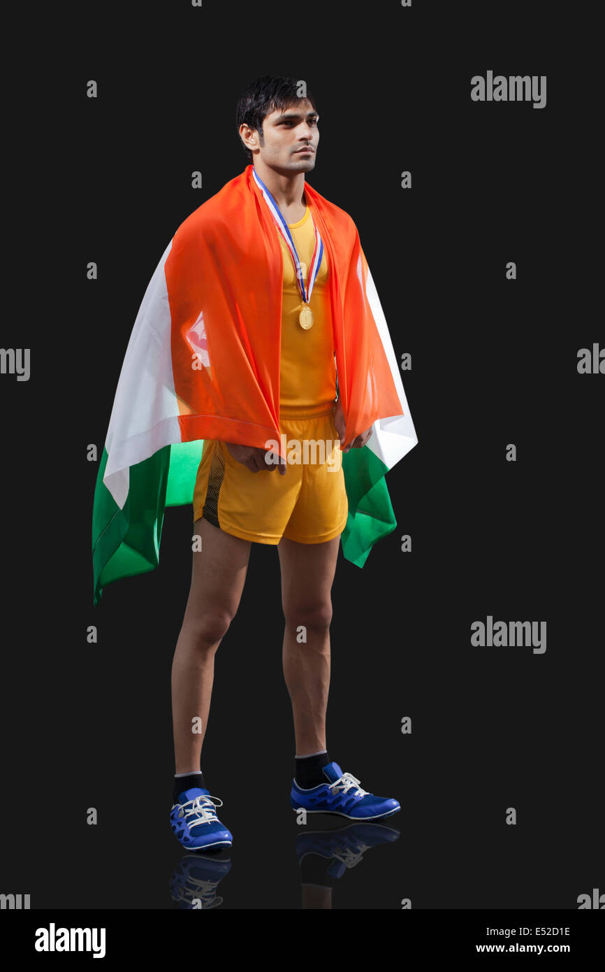 Toute la longueur du jeune homme avec drapeau indien médaillé à l'extérieur contre fond noir Banque D'Images