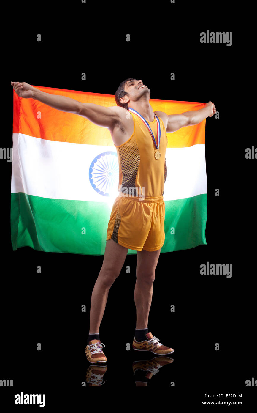 Toute la longueur du drapeau indien holding médaillé d'hommes qu'il en a l'air jusqu'au fond noir Banque D'Images