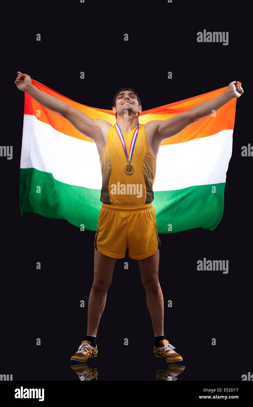 Toute la longueur de l'heureux homme médaillé olympique avec drapeau indien sur fond noir permanent Banque D'Images
