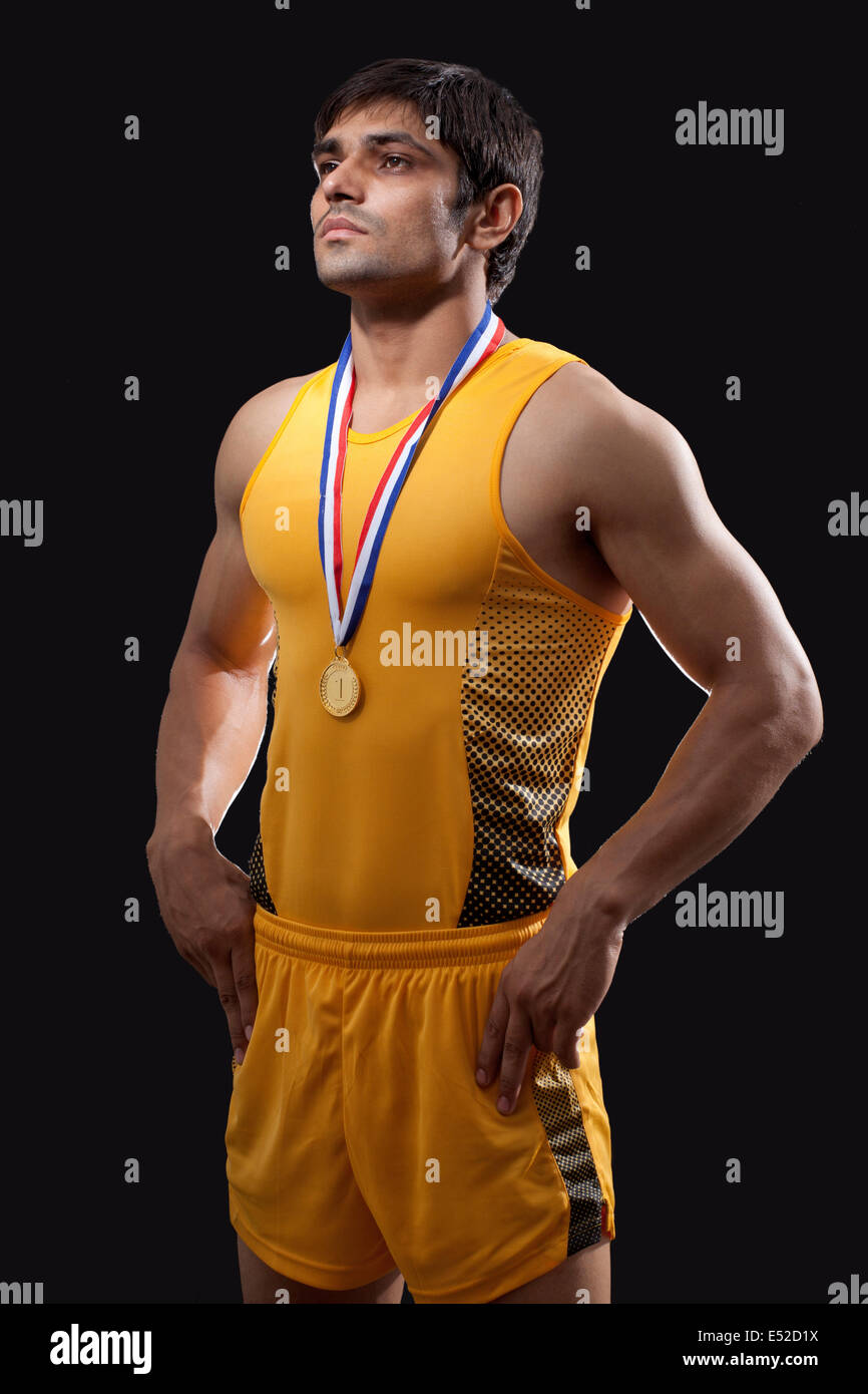 Médaillé d'or mâle debout avec les mains de taille sur fond noir Banque D'Images